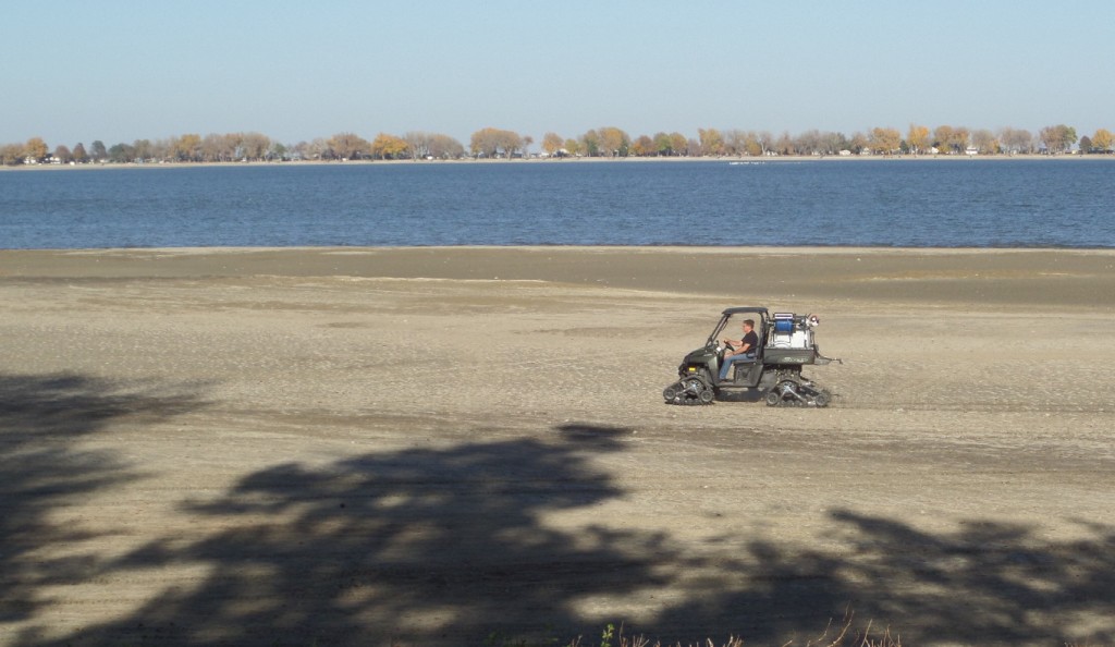 Kent Aden uses his personal utility vehicle to spray an aquatic herbicide on the shoreline at Johnson Lake.
